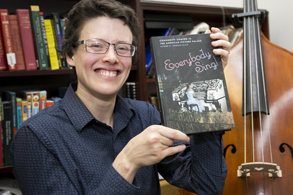 Esther Morgan-Ellis holding a copy of her book Everybody Sing!